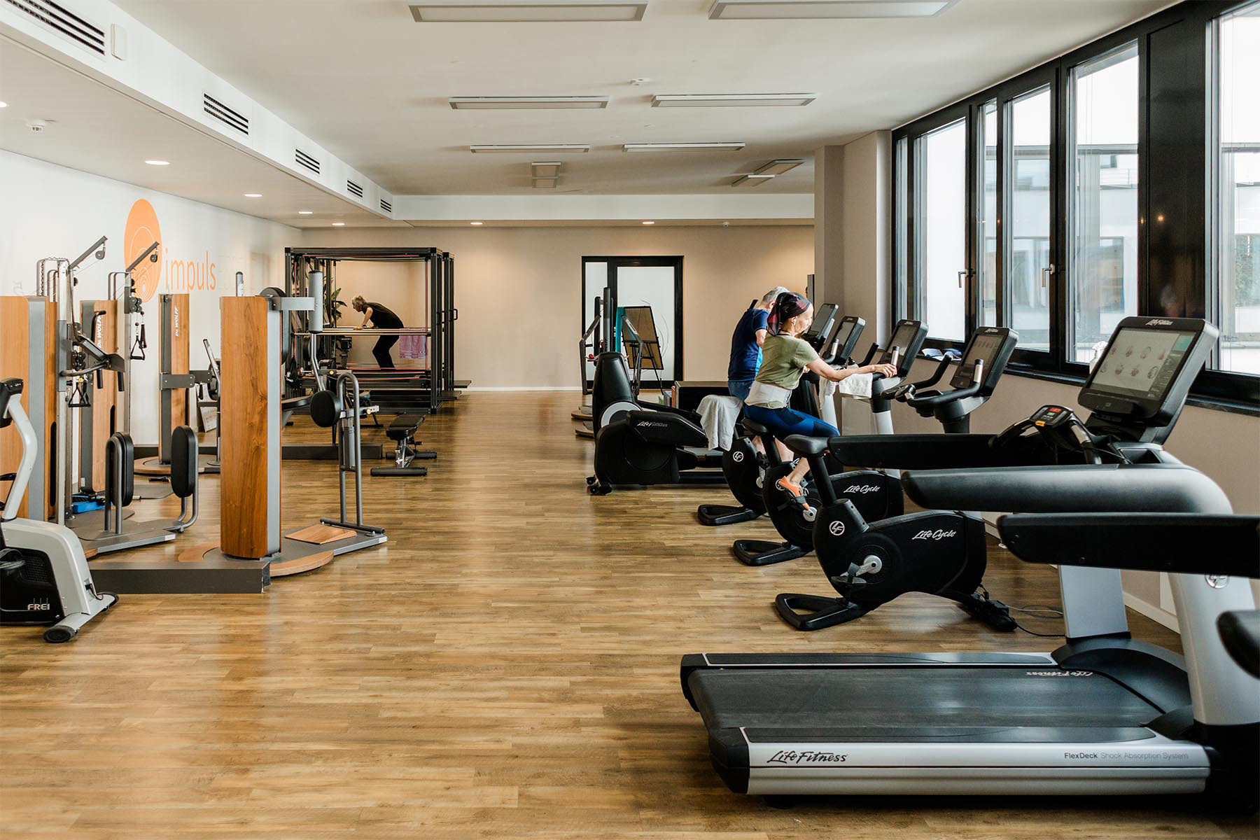 Heller Fitnessbereich mit modernen Trainingsgeräten und großzügiger Fensterfront in stilvoller Studioatmosphäre - impulsESSENZ in Böblingen
